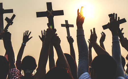 hands raised with Christian crosses